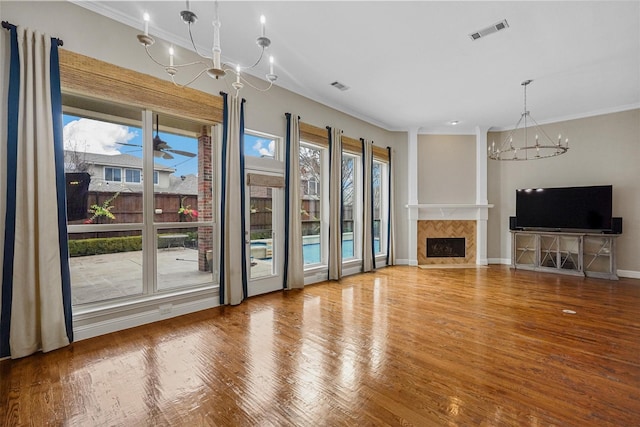 unfurnished living room with hardwood / wood-style flooring, a tile fireplace, a healthy amount of sunlight, and crown molding