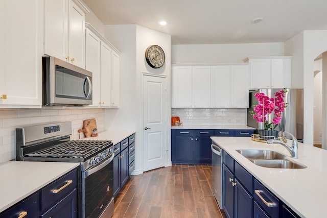 kitchen with appliances with stainless steel finishes, blue cabinets, sink, and white cabinets