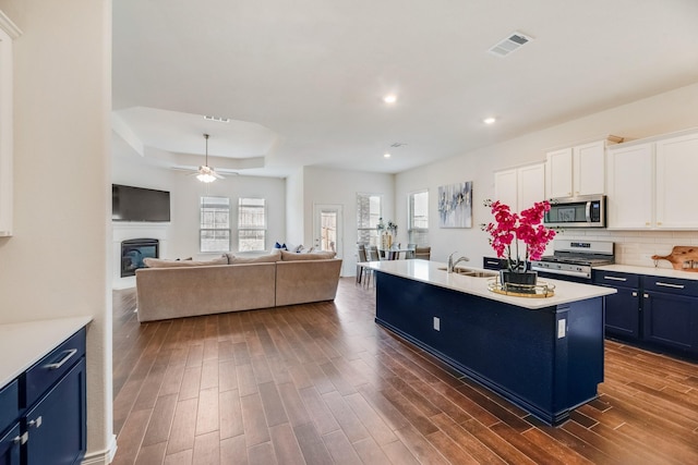 kitchen featuring sink, dark wood-type flooring, appliances with stainless steel finishes, a kitchen island with sink, and white cabinets