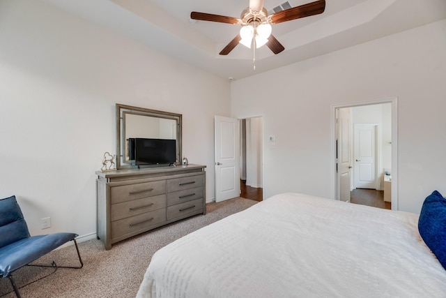 carpeted bedroom featuring a raised ceiling and ceiling fan