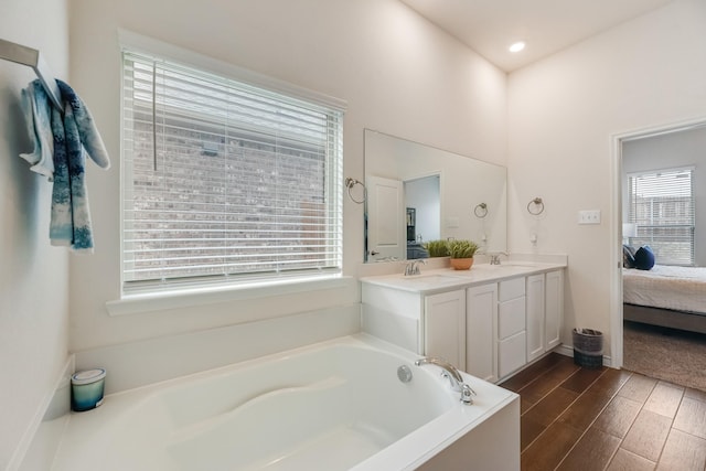 bathroom with hardwood / wood-style flooring, vanity, and a bath