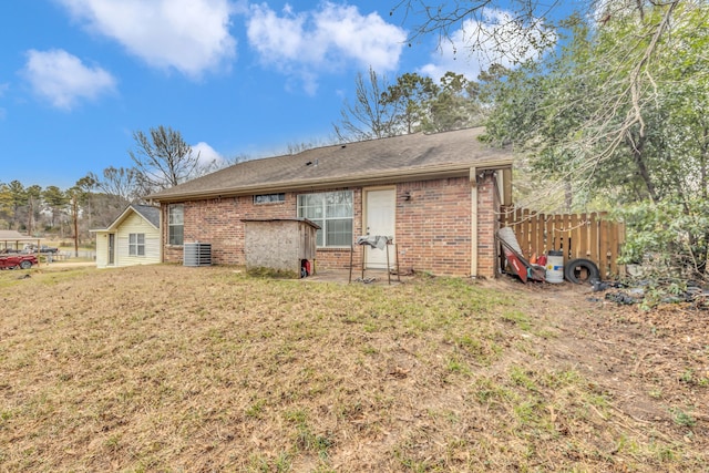 rear view of property featuring central AC and a lawn