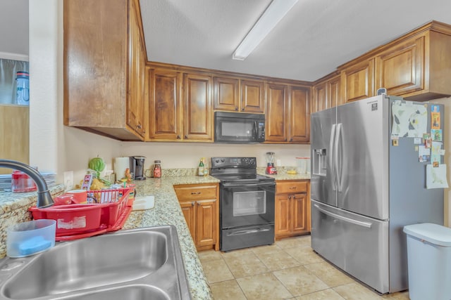 kitchen featuring sink, light stone counters, a textured ceiling, light tile patterned floors, and black appliances