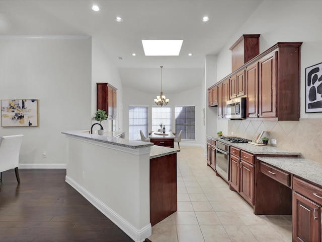 kitchen featuring pendant lighting, appliances with stainless steel finishes, tasteful backsplash, a notable chandelier, and light stone countertops