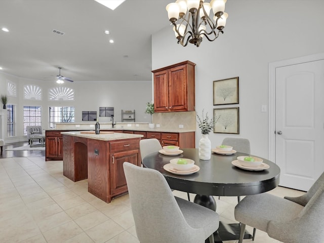 kitchen featuring light tile patterned flooring, a kitchen island, pendant lighting, decorative backsplash, and kitchen peninsula