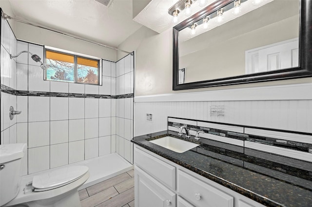 bathroom featuring vanity, toilet, and a tile shower