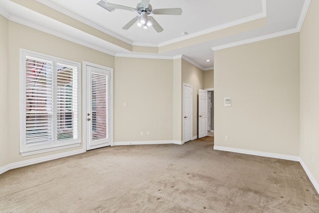 carpeted spare room with a raised ceiling, ornamental molding, and ceiling fan