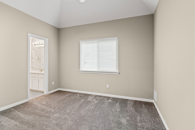 carpeted spare room featuring vaulted ceiling