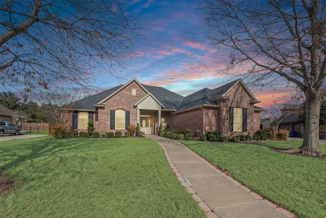 view of front of property featuring brick siding, a front lawn, and a shingled roof