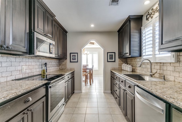 kitchen with stainless steel appliances, light tile patterned flooring, sink, and decorative backsplash