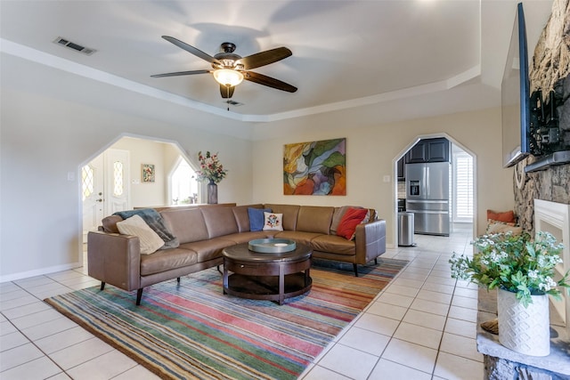 tiled living room featuring a fireplace, a raised ceiling, and a wealth of natural light