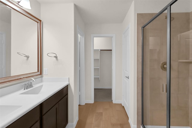 bathroom with walk in shower, vanity, and hardwood / wood-style floors