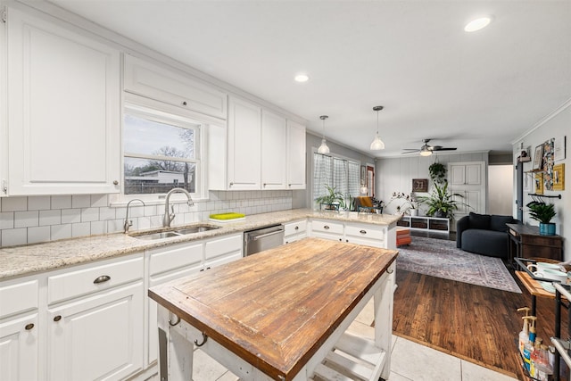 kitchen featuring sink, white cabinetry, a center island, stainless steel dishwasher, and pendant lighting