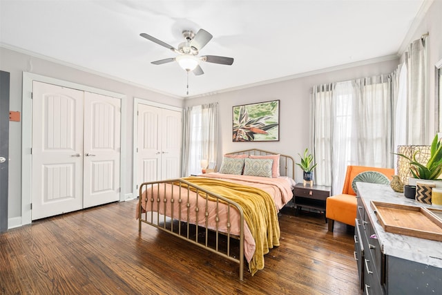 bedroom with dark hardwood / wood-style flooring, two closets, ornamental molding, and ceiling fan