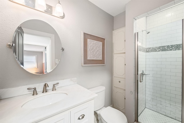 bathroom featuring a shower with door, vanity, and toilet