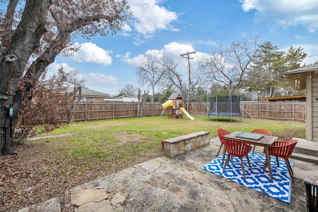 view of yard featuring a patio, a playground, and a trampoline