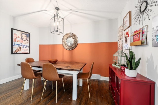 dining space with dark wood-type flooring and an inviting chandelier