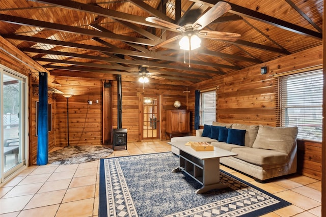 living room with light tile patterned flooring, wood walls, wooden ceiling, and a wood stove