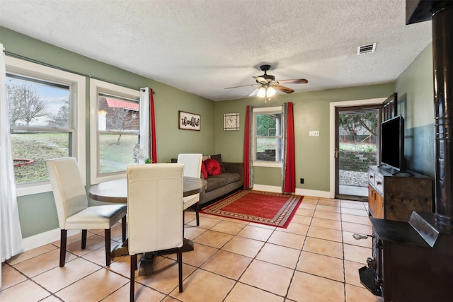 tiled dining room with a textured ceiling and ceiling fan