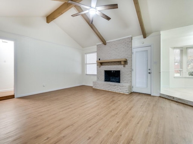 unfurnished living room with ceiling fan, a fireplace, lofted ceiling with beams, and light wood-type flooring