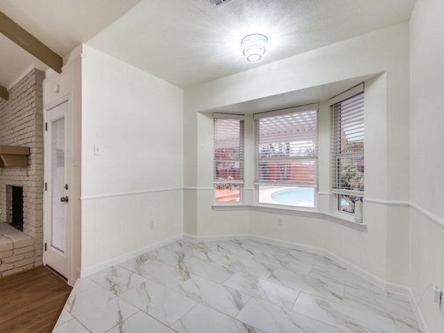 spare room with a textured ceiling and a fireplace