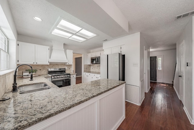 kitchen featuring a sink, custom range hood, light stone countertops, and stainless steel appliances