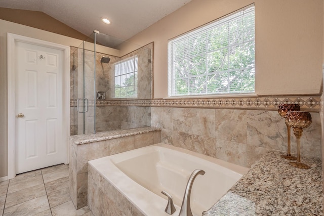 full bath featuring vaulted ceiling, a shower stall, a bath, wainscoting, and tile walls