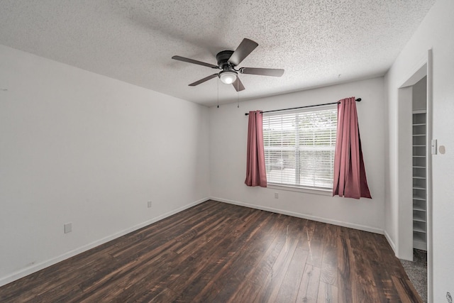unfurnished room with a ceiling fan, baseboards, a textured ceiling, and dark wood finished floors