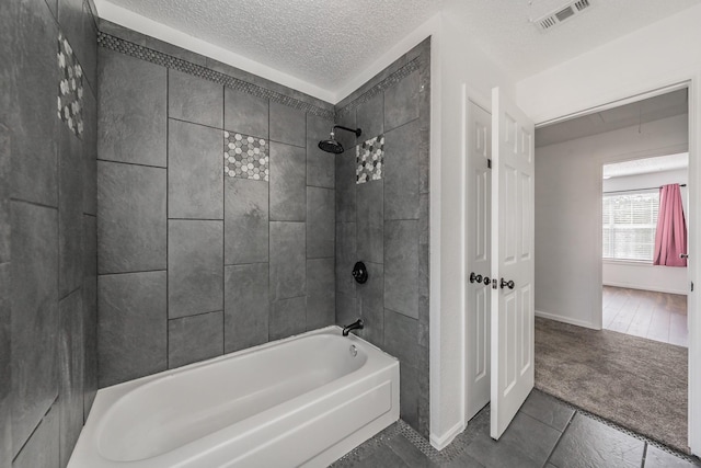 bathroom featuring bathing tub / shower combination, visible vents, and a textured ceiling