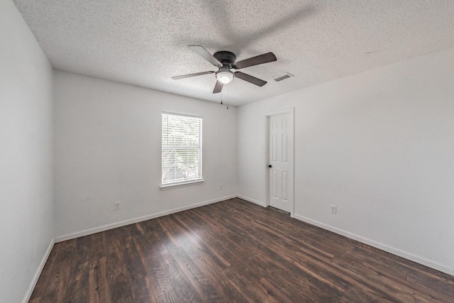 unfurnished room with baseboards, visible vents, dark wood-style flooring, and a ceiling fan