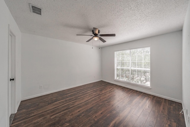 spare room with a textured ceiling, a ceiling fan, visible vents, dark wood-style flooring, and baseboards