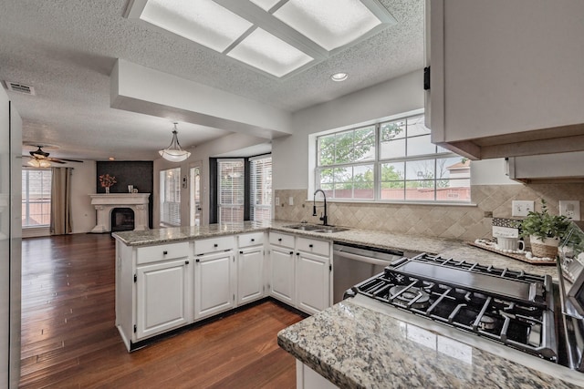 kitchen with a sink, visible vents, a peninsula, and a textured ceiling