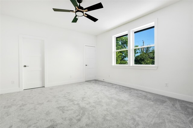 unfurnished bedroom featuring light colored carpet, ceiling fan, and a closet