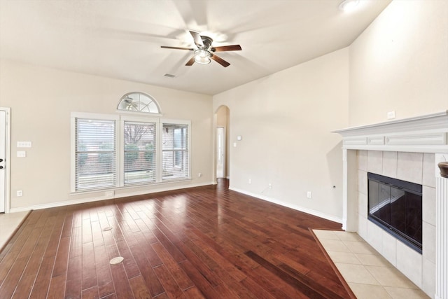 unfurnished living room with ceiling fan, a fireplace, and light wood-type flooring