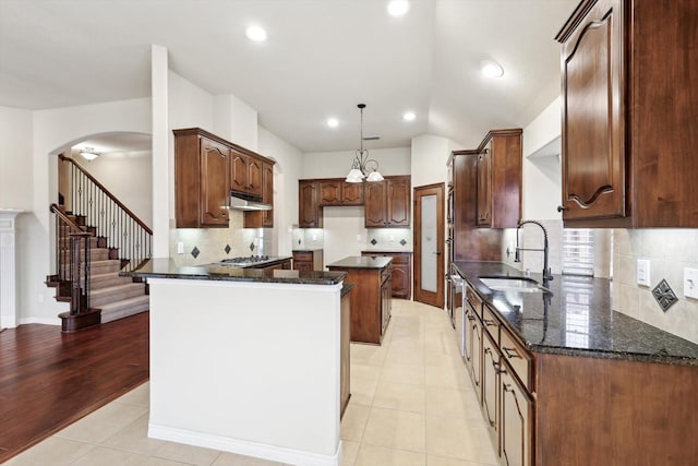 kitchen featuring dark stone counters, a center island, sink, and light tile patterned floors