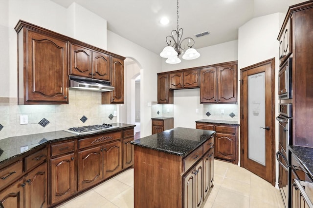 kitchen with stainless steel appliances, a center island, decorative backsplash, and dark stone counters