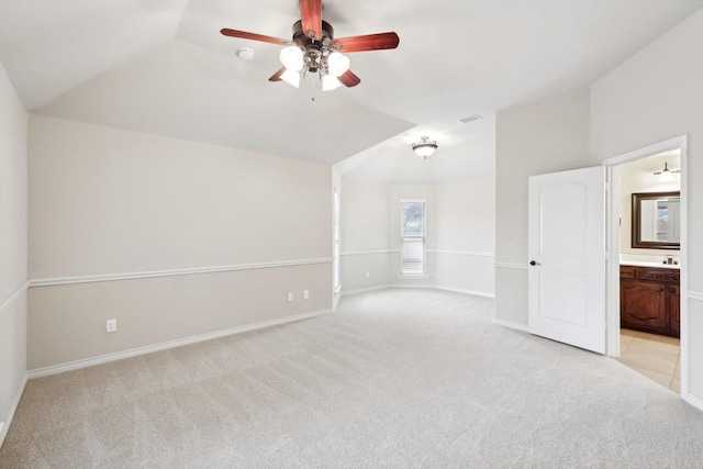 interior space with light carpet, ensuite bath, lofted ceiling, and ceiling fan