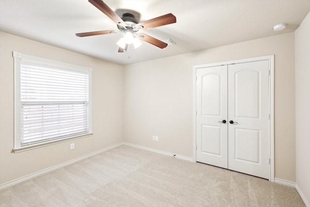 unfurnished bedroom with ceiling fan, light colored carpet, and a closet