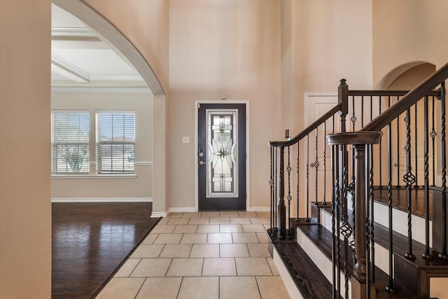 entryway with a high ceiling, ornamental molding, and light hardwood / wood-style flooring