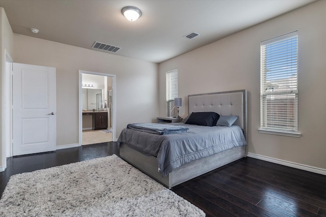 bedroom featuring dark wood-type flooring and ensuite bath