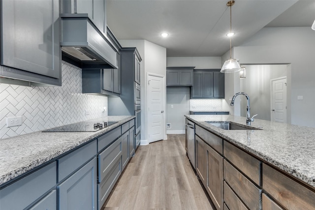 kitchen featuring pendant lighting, sink, stainless steel appliances, light stone countertops, and custom range hood