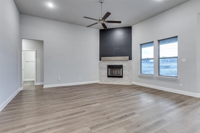 unfurnished living room featuring a towering ceiling, light hardwood / wood-style flooring, and ceiling fan