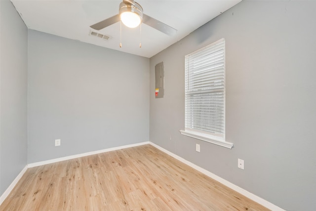 spare room with ceiling fan, electric panel, and light hardwood / wood-style floors