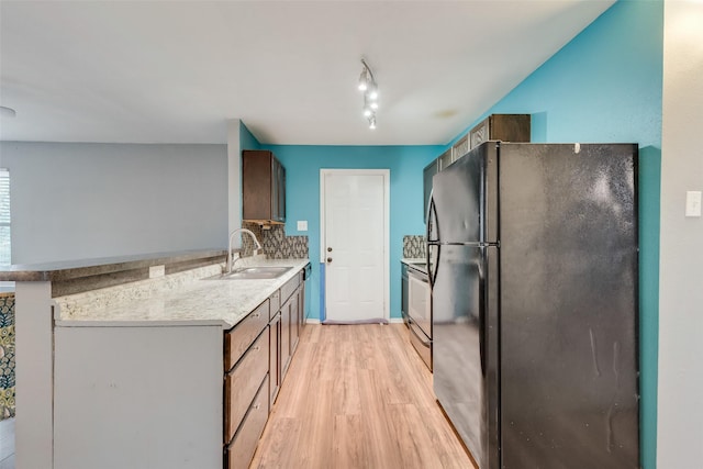 kitchen with sink, light wood-type flooring, black refrigerator, stainless steel electric stove, and decorative backsplash