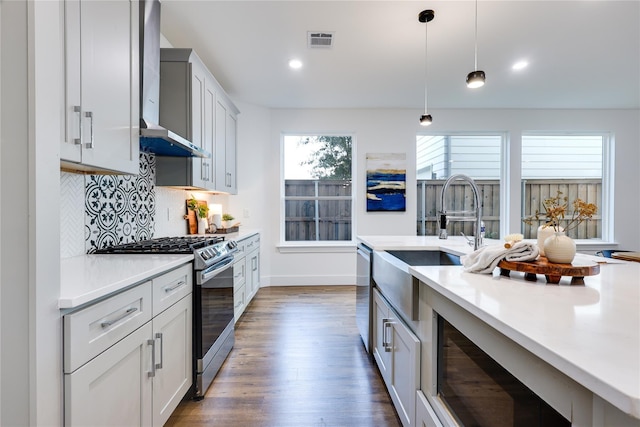 kitchen with decorative light fixtures, appliances with stainless steel finishes, dark hardwood / wood-style flooring, decorative backsplash, and wall chimney range hood