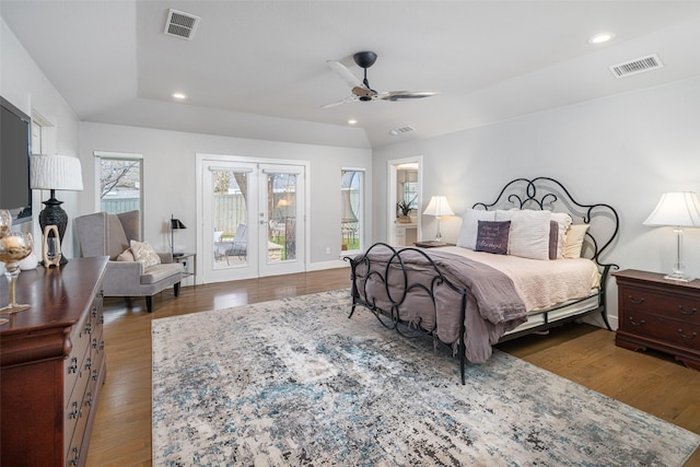 bedroom featuring dark wood-type flooring, french doors, a tray ceiling, ceiling fan, and access to exterior