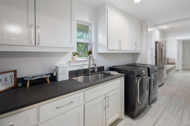 laundry room with separate washer and dryer, sink, and cabinets