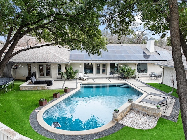 view of swimming pool featuring a trampoline, a lawn, and a patio