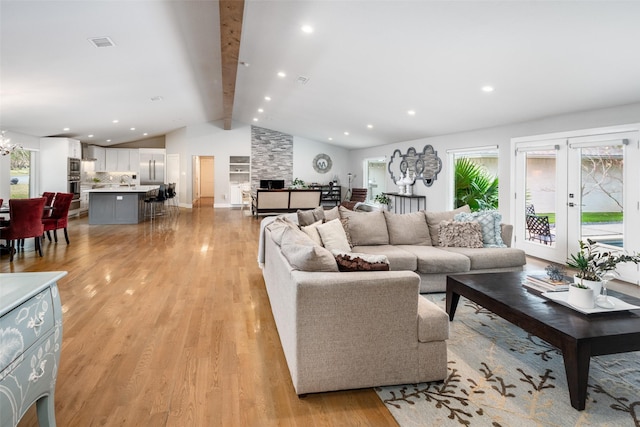 living room featuring lofted ceiling with beams, sink, french doors, and light hardwood / wood-style flooring