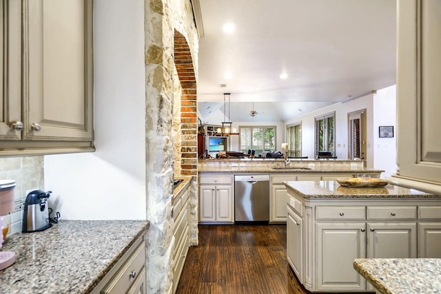 kitchen featuring tasteful backsplash, light stone counters, stainless steel dishwasher, decorative light fixtures, and dark hardwood / wood-style floors